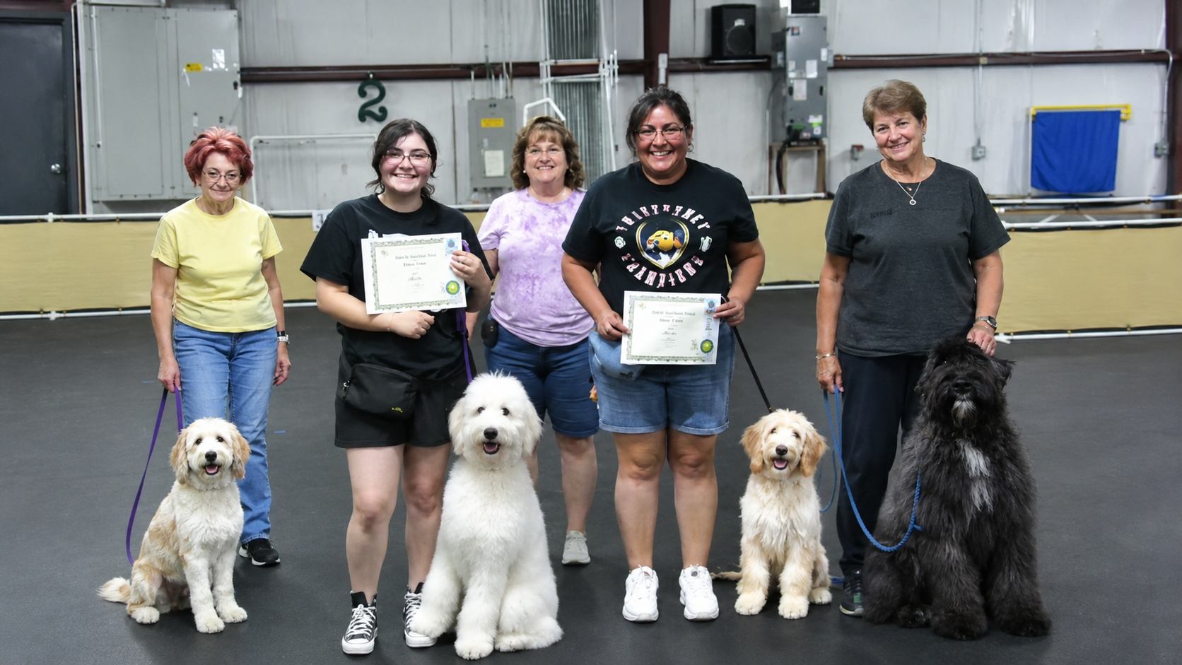 Five IPOC members and their dogs holding graduation certificates after completing a training session
